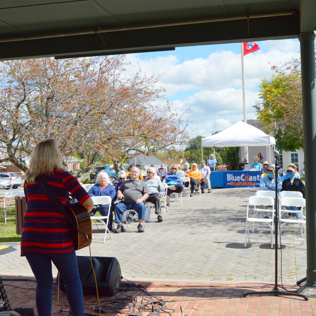 someone playing music at the depot museum while people watch