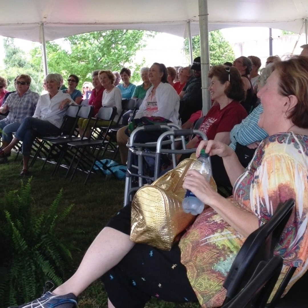 group of people under a tent laughing at the stage 