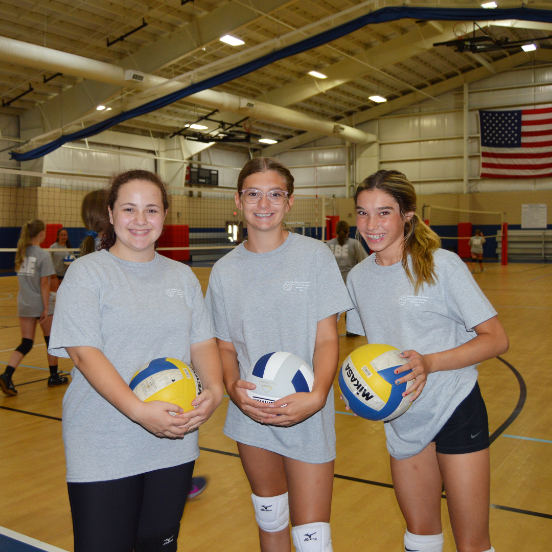 three girls holding volleyballs